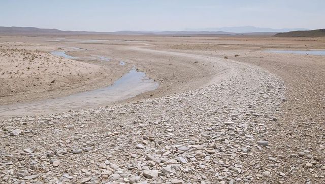 Meandering dry riverbed with pebble banks and shallow meandering channels in arid floodplain