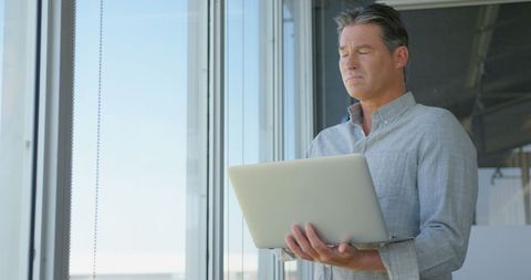 Focused Executive Using Laptop in Modern Office Environment