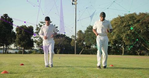 Two cricketers running agility drills on grassy park field with cones and digital overlay