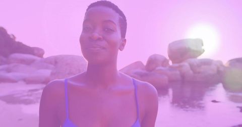 Woman in Blue Swimwear Standing in Serene Bay Among Glowing Boulders