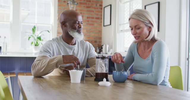 Biracial senior couple talking to each other while having coffee at home. retirement senior couple lifestyle living concept