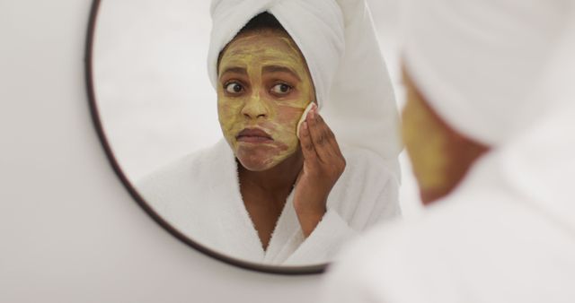 Happy african american woman cleaning beauty mask in bathroom. domestic lifestyle, spending free time at home.