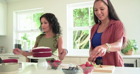 Diverse friends baking red velvet cake together at bright modern kitchen island