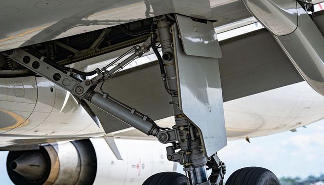 Aircraft landing gear close-up showing twin-wheel bogie, oleo strut and hydraulic actuators