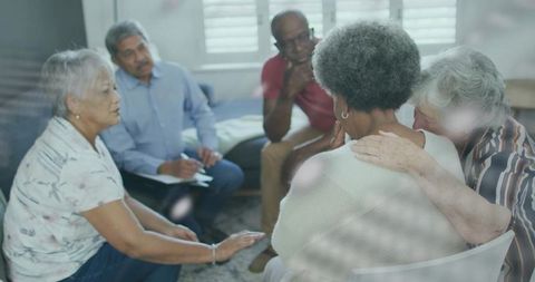 Diverse support group comforting senior woman in living room