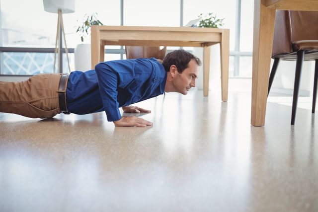 Executive in business attire performing push-ups on office floor. Ideal for illustrating workplace wellness, corporate fitness programs, and balancing work with health. Can be used in articles about maintaining physical fitness in a professional environment or promoting healthy office habits.