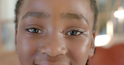 Smiling african girl gazing at window reflections in warm indoor closeup portrait