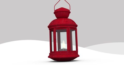 Red lantern with burning candle against winter background