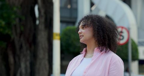African american woman standing and looking right on urban street wearing pink shirt