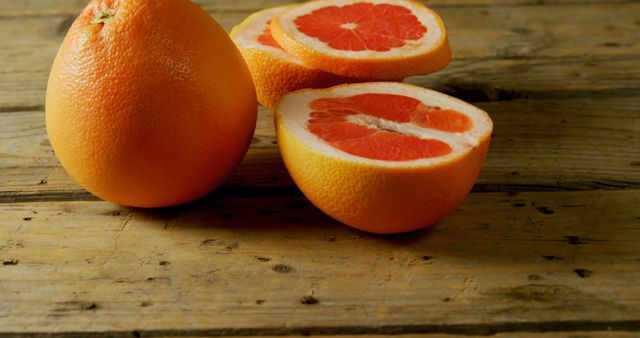Slices of ripe grapefruit displayed on a rustic wooden surface. Perfect for health and wellness articles, food blogs, culinary websites, or nutrition content. Highlights freshness and natural food themes.