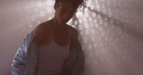 African american woman standing in soft studio light wearing satin jacket and tank top