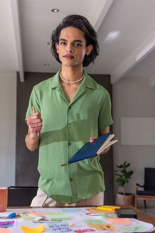Asian man holding notebook and leading sticky-note brainstorming session in modern office