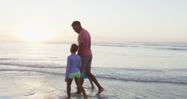 Father and daughter are walking along beach at sunset, enjoying bonding time. Ideal for content about family outings, parent-child relationships, seaside relaxation, and summer activities. Great for use in promotions about travel, family vacations, recreational activities, and lifestyle blogs.