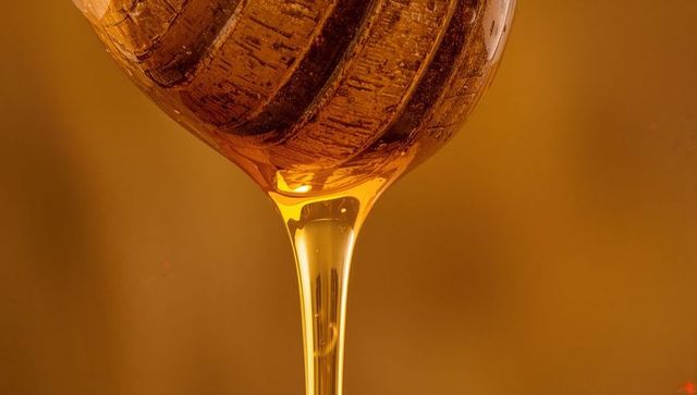 Dripping Golden Honey from Wooden Dipper Highlighting Rich Texture