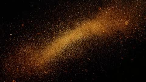 Golden powder exploding into sweeping curved arc with sparkling glitter on black backdrop