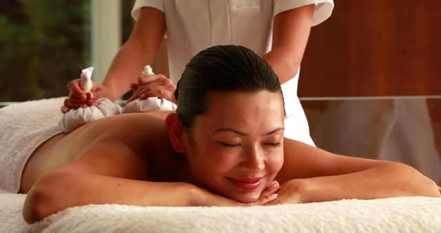 Gorgeous woman getting a massage with herbal compresses in the health spa