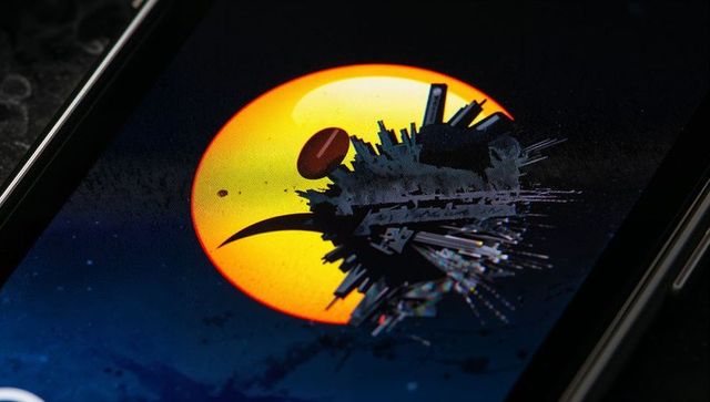 Smartphone displaying futuristic neon city silhouette against glowing orange orb macro
