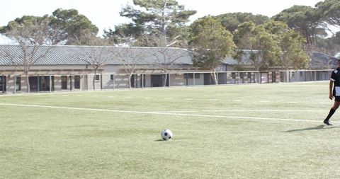Determined youth kicking soccer ball on field