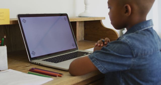 African american boy at home in online school class, using laptop with copy space on screen. staying at home in isolation during quarantine lockdown.