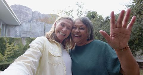 Diverse mature women taking selfie embraced outdoors