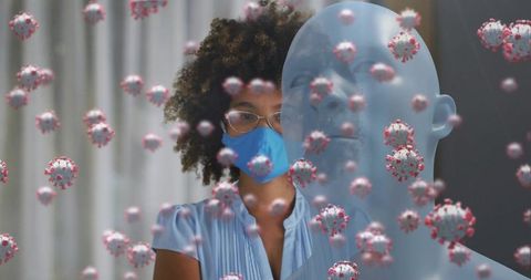 Masked woman standing amid floating virus particles and translucent medical silhouette