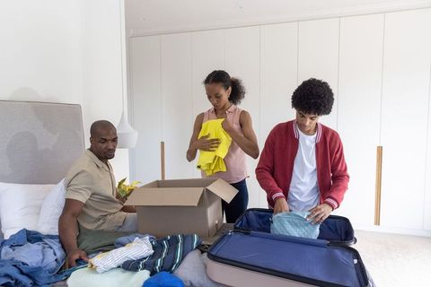 Black family packing and sorting clothes in bedroom preparing for move or family trip