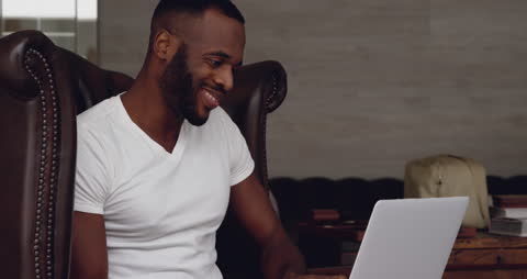 Smiling Man Working on Laptop at Home