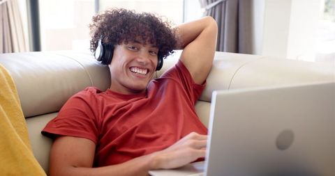 Young Man Relaxing on Couch with Laptop and Headphones