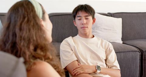 Young man listening intently during intimate living room conversation on gray couch