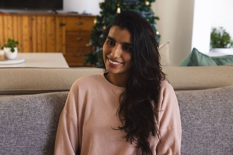 Joyful young woman in cozy home by festive christmas tree