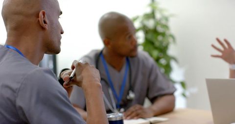 African american healthcare team collaborating at clinic meeting table in scrubs