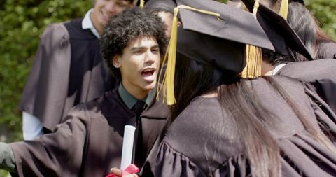 Graduating Students Celebrating on Campus Lawn Holding Diplomas and Tassel Caps