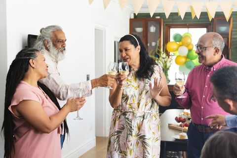 Diverse friends toasting with wine around kitchen island during casual home celebration