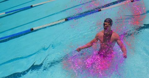 Triumphant swimmer emerging from lane while splashing vibrant pink particles