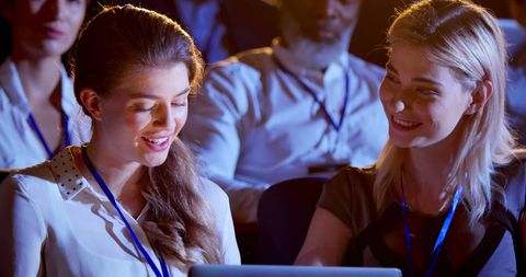 Businesswomen Collaborating on Laptop at Seminar