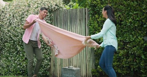 Couple Spreading Picnic Blanket in Garden Setting