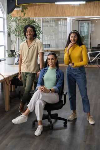 Diverse young professionals posing in modern open-plan office with plants and bicycle