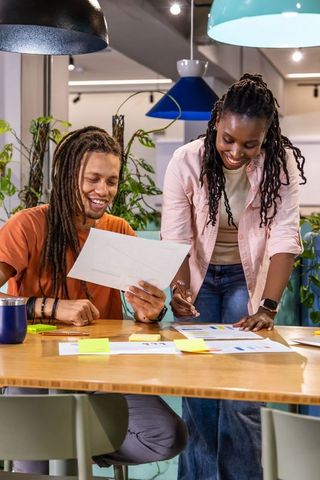 African american coworkers collaborating over charts and sticky notes in coworking space