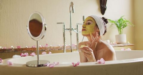 Relaxed Woman in Bathtub Applying Face Mask for Self-Care