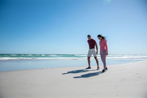Happy Couple Strolling on Sunny Beach with Clear Blue Sky