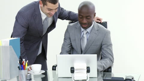 Businessmen Collaborating on Project Using Laptop in Office