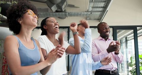 Diverse colleagues applauding in modern office environment