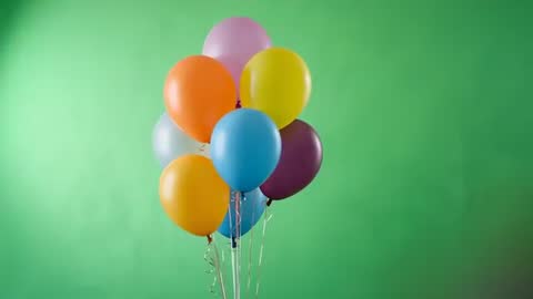 Vibrant Balloons Swaying in Studio on Green Backdrop