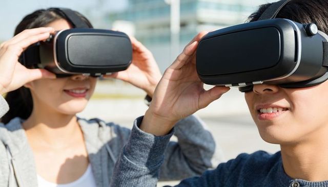 Young adults exploring virtual reality with black vr headsets outdoors in urban plaza