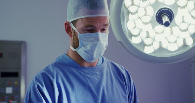 Caucasian male surgeon wearing face mask during surgery in operating room. Hospital, medicine and healthcare, unaltered.