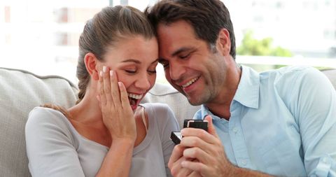 Surprised Couple Sharing Gift on Couch at Home