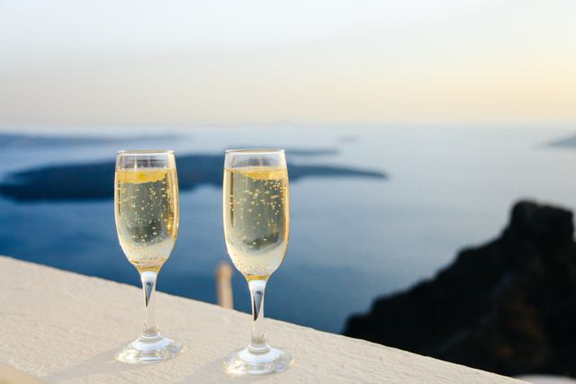 Showing two Champagne glasses on railing with a stunning ocean backdrop at sunset. Highlighting themes of celebration, relaxation, and luxurious travel experiences. Perfect for advertisements for resorts, honeymoon packages, and high-end events. Captures romantic and vacation motifs.