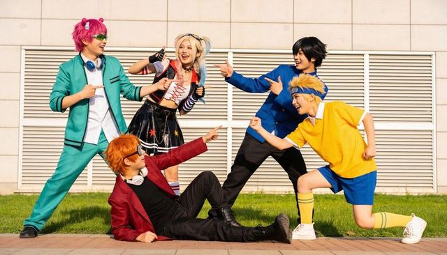 Colorful cosplayers laughing and pointing on sunny urban walkway with bold costumes