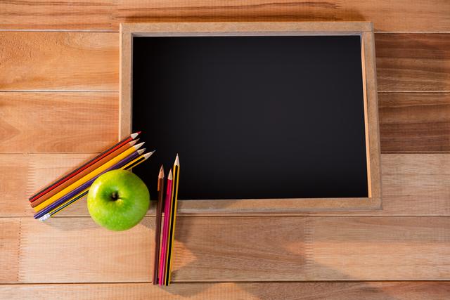 Close-up of chalkboard with colored pencil and apple on a table 4k