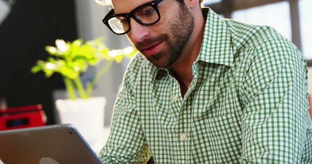 Young Man in Green Plaid Shirt Using Tablet at Home - Download Free Stock Images Pikwizard.com